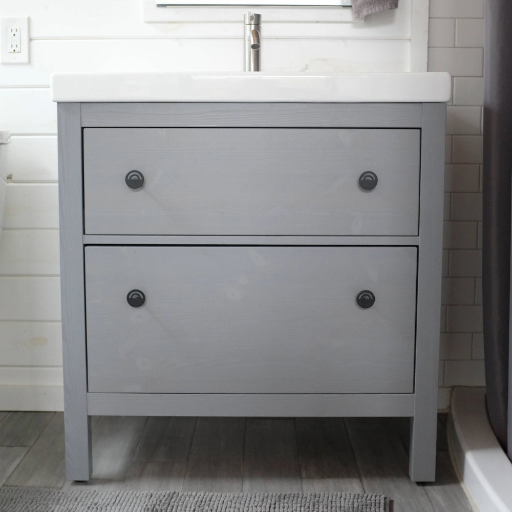 Horizon matte black knobs installed on pale blue bathroom vanity