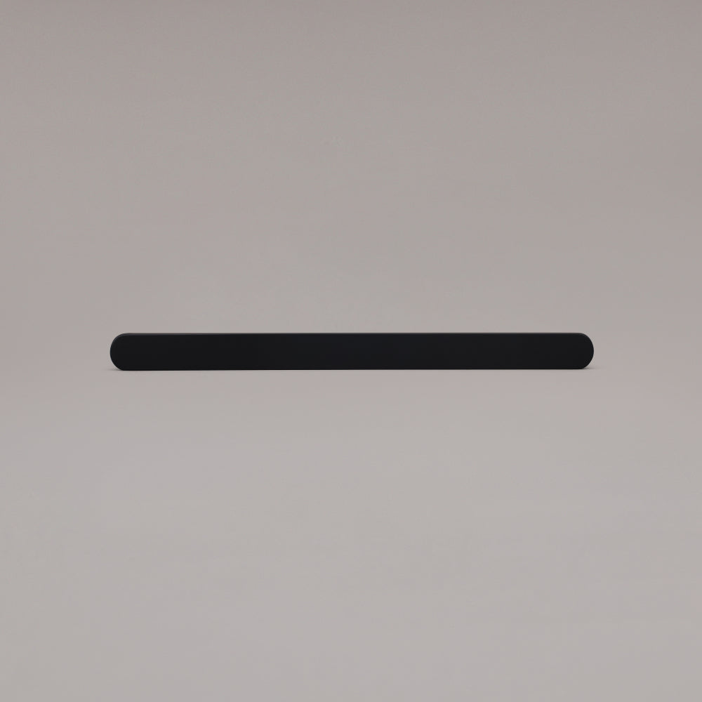 12" Ribbed appliance pull in Matte Black laying on gray background