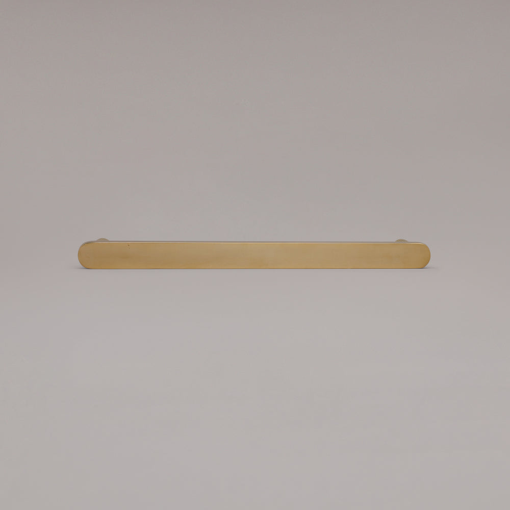 12" Ribbed appliance pull in Unlacquered Polished Brass laying on gray background