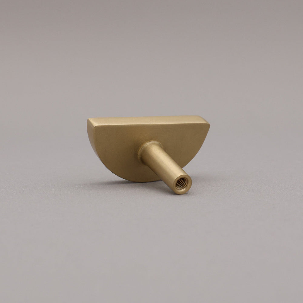 satin brass gold half-circle half moon cabinet knob on gray background