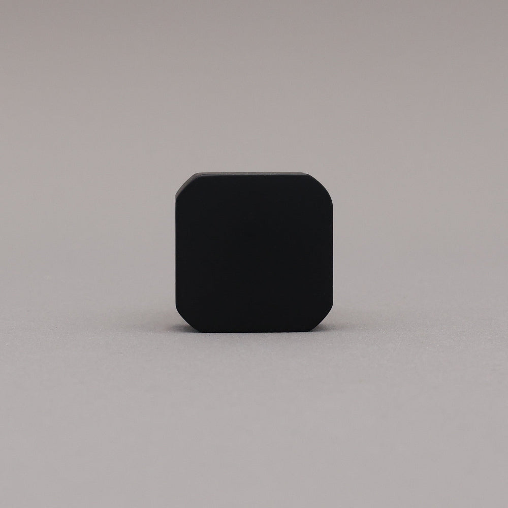 Black and brass gold square knob on a gray background