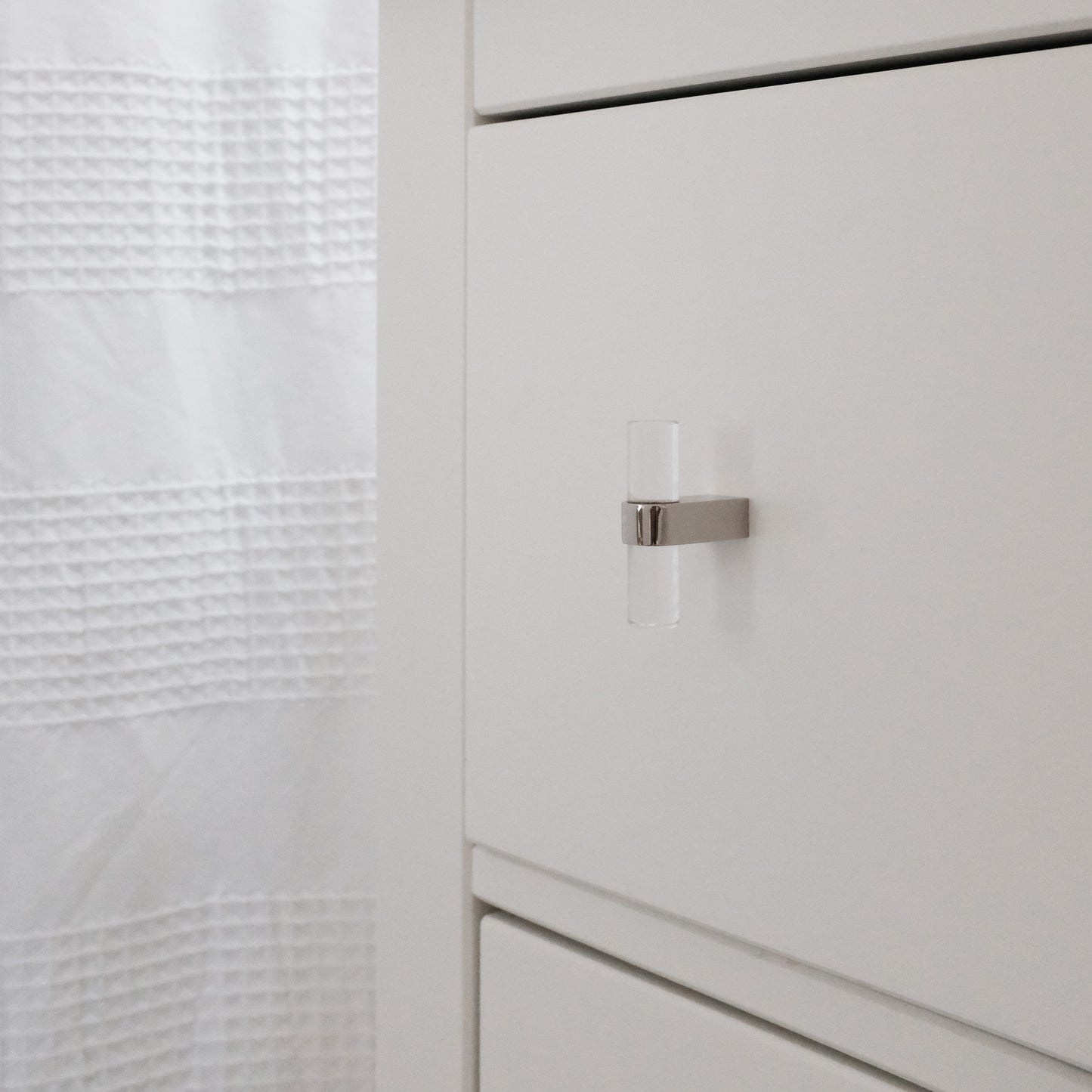 Polished Nickel Acrylic Knob on white bathroom vanity with shower curtain