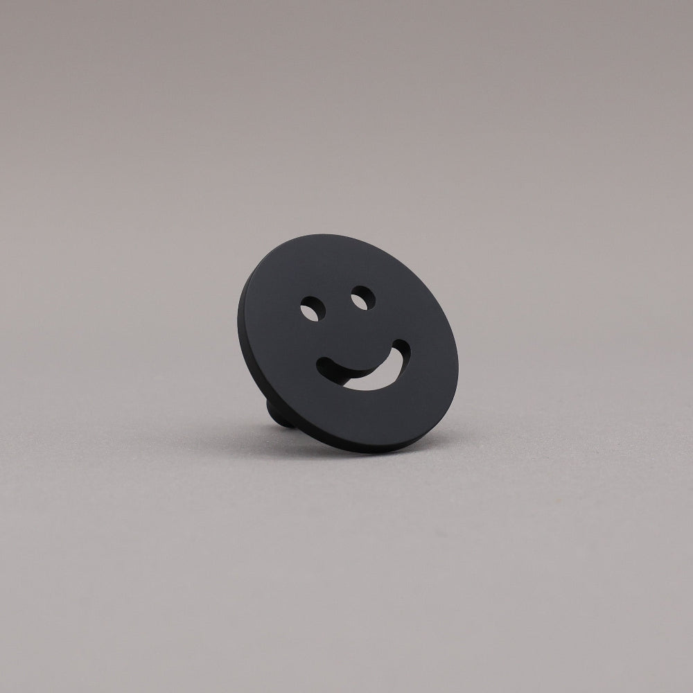Matte Black smiley face object on a gray background