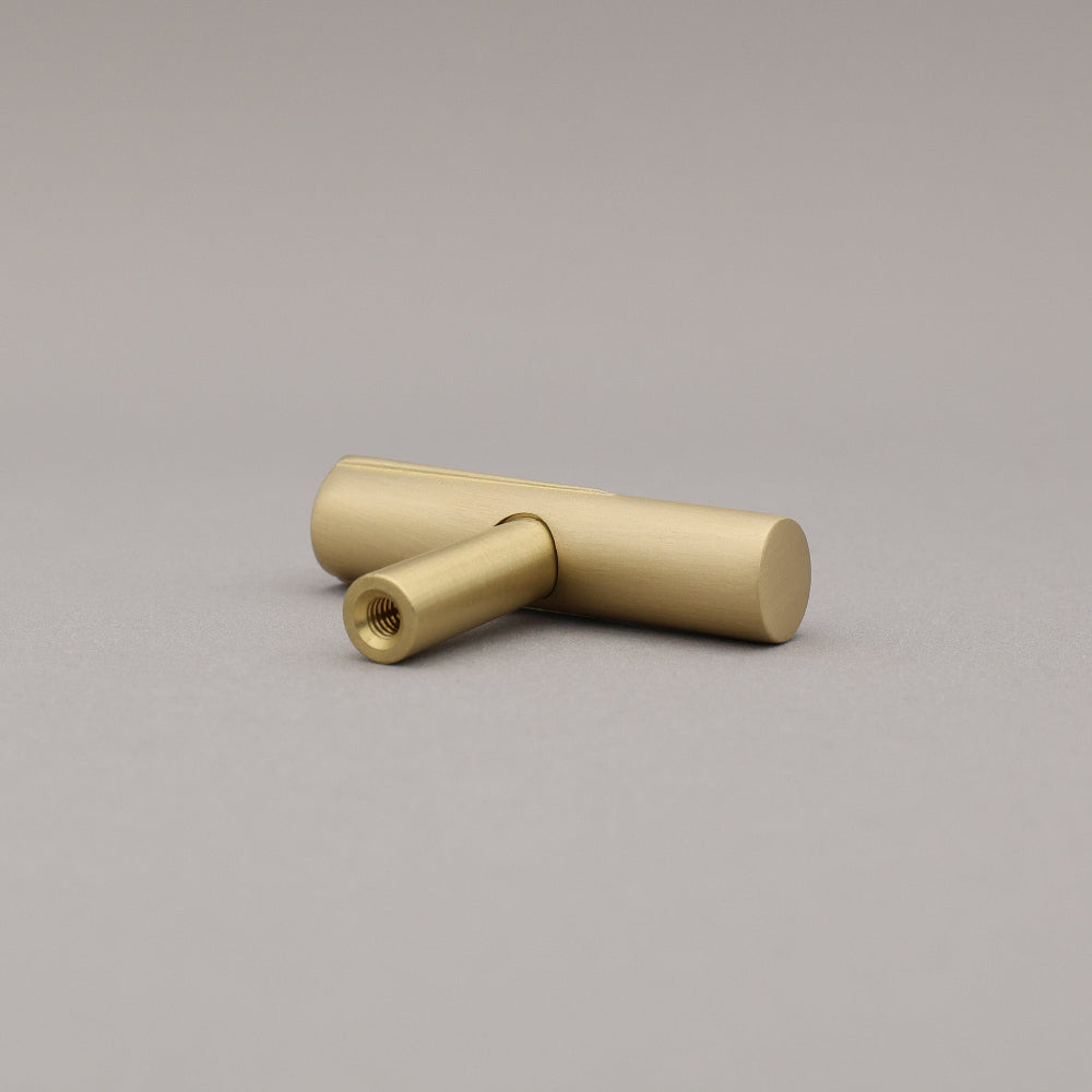 Sunburst t-knob in satin brass gold on a gray background rear view