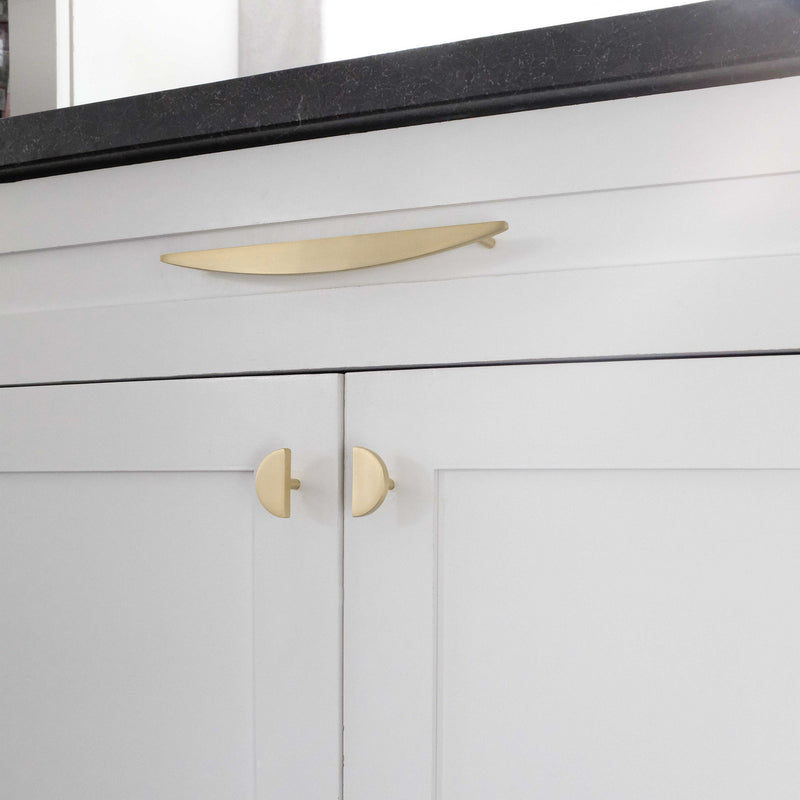 Gold cabinet knobs mixed with gold cabinet pull on white kitchen cabinets with black counter