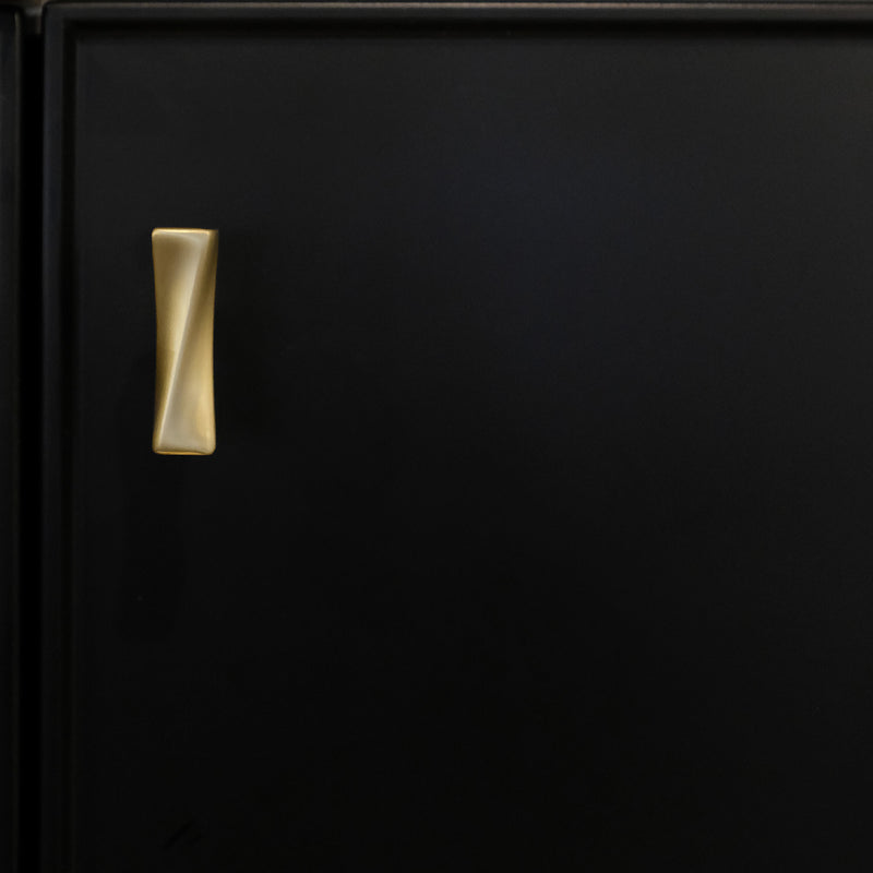 Black cabinet panel with gold cabinet knob with twist in satin brass