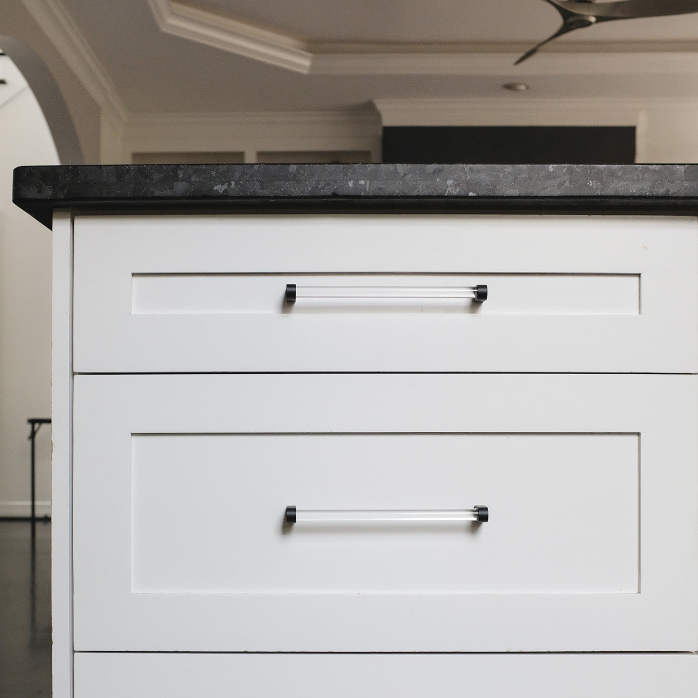 Two eight inch black acrylic pulls on white shaker kitchen drawers in a kitchen.