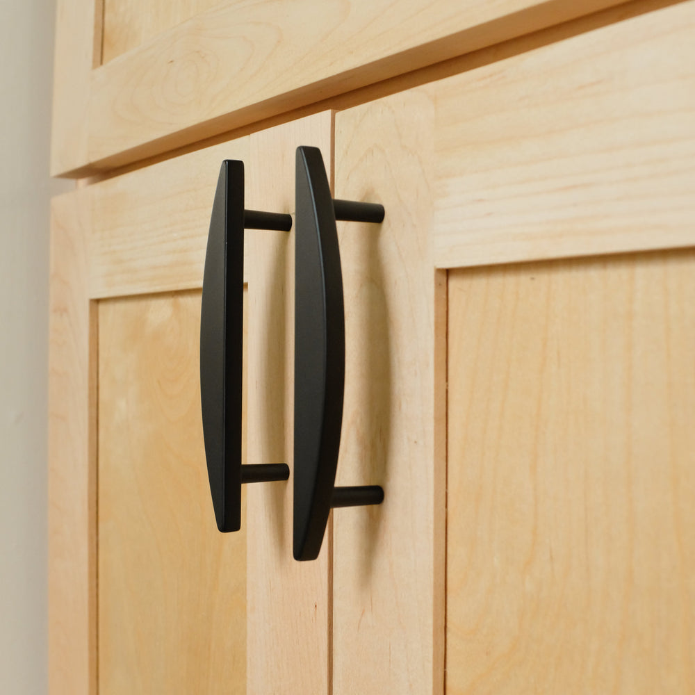 Black kitchen cabinet pulls on wooden cabinet doors. 