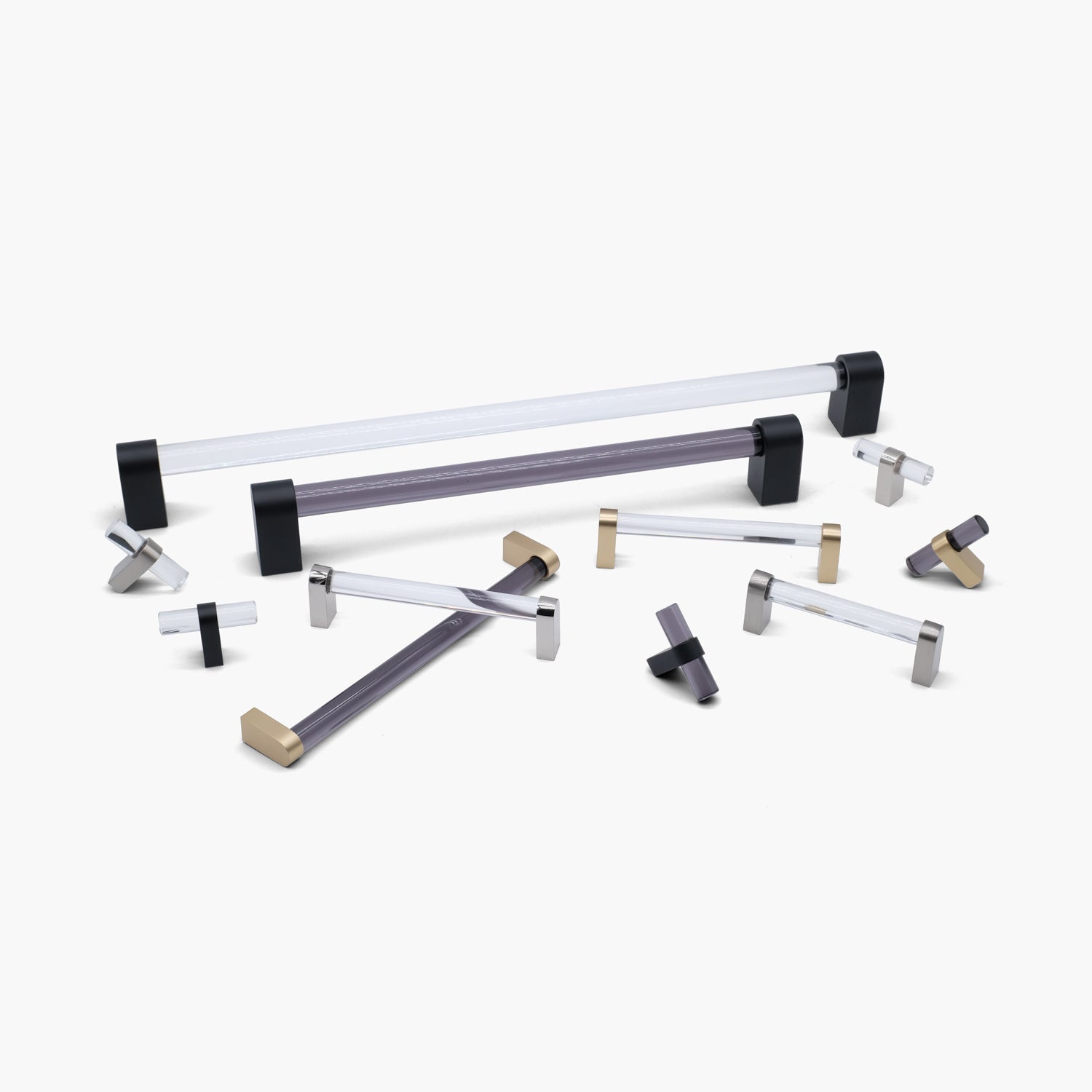 Scattered hardware pieces of acrylic cabinet hardware from the Hapny Clarity Collection in Smoke and Clear Acrylic in Black, Brass, and Nickel finishes.