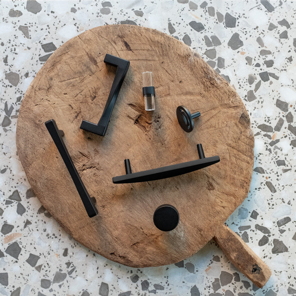 Matte Black Cabinet Pulls and Knobs on a cutting board on terrazzo counter