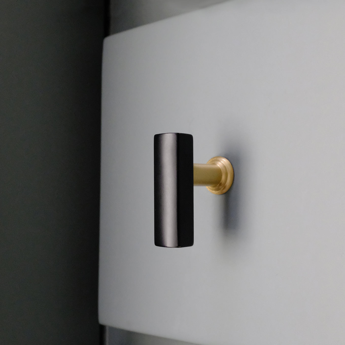 Black and brass cabinet hardware on a blue bathroom drawer.