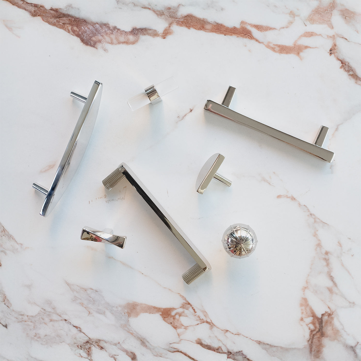 Polished Nickel knobs, handles, and pulls on marble background