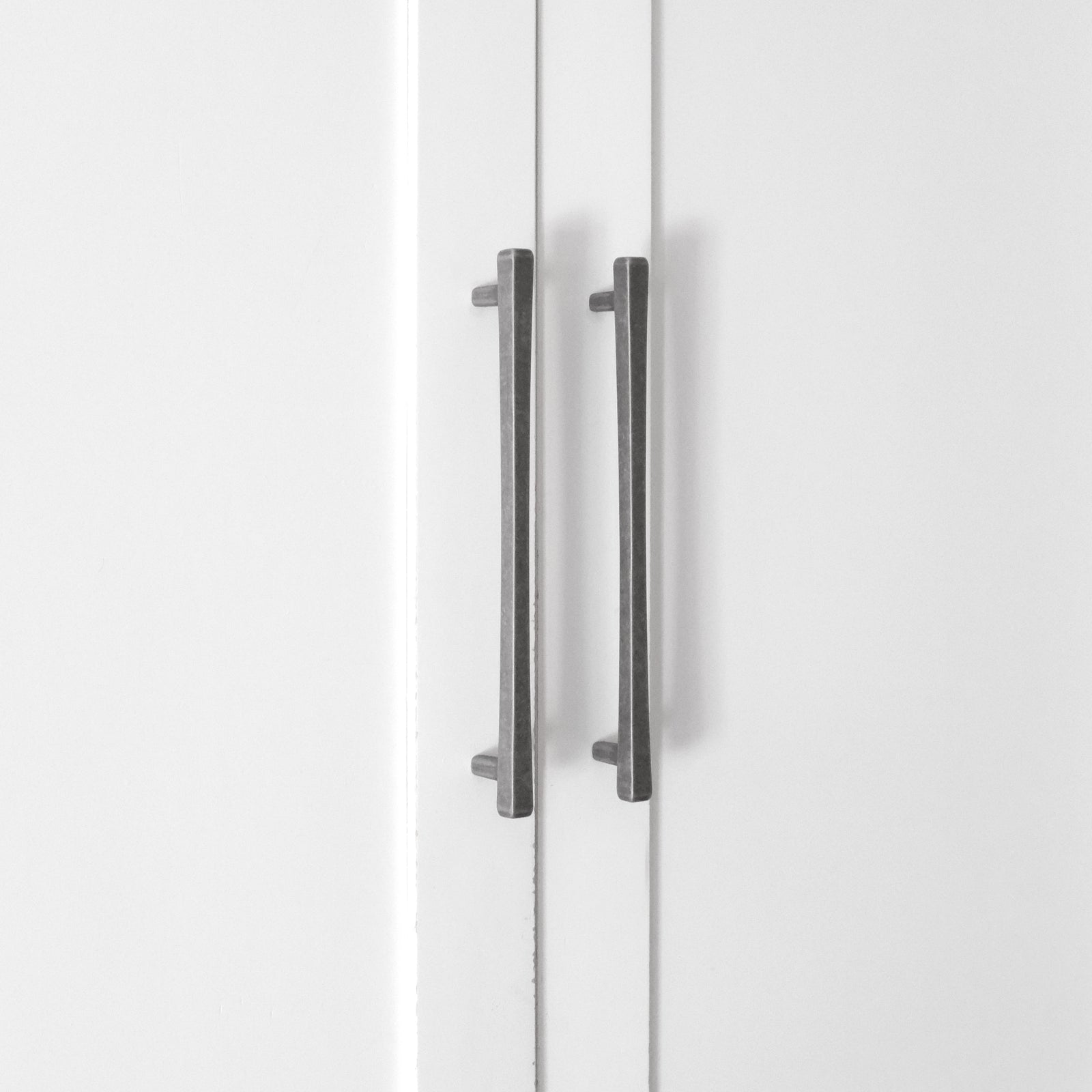 Modern cabinet pulls in weathered nickel on white kitchen cabinets.