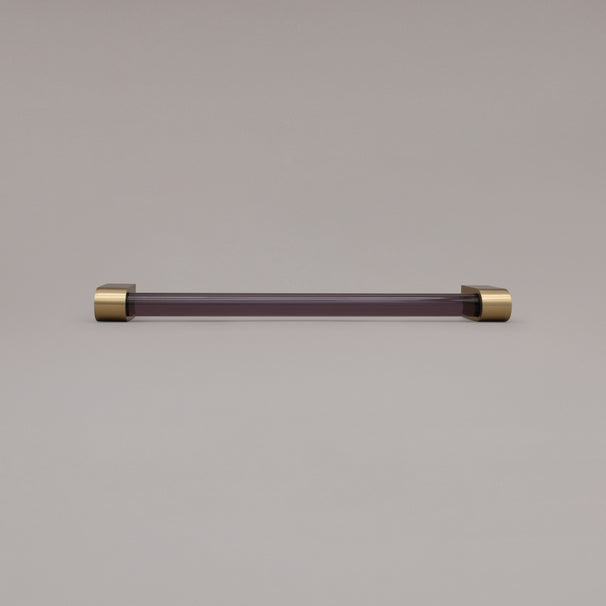 Clarity smoke acrylic and satin brass stems 12 inch appliance pull laying on gray background