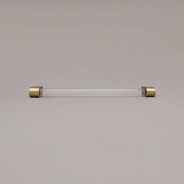 Clarity clear acrylic and satin brass stems 12 inch appliance pull laying on gray background