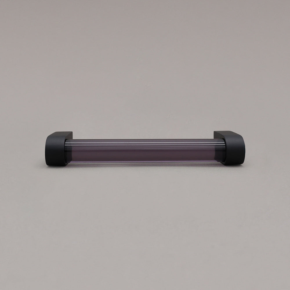 small smoke and matte black cabinet pull laying on gray background