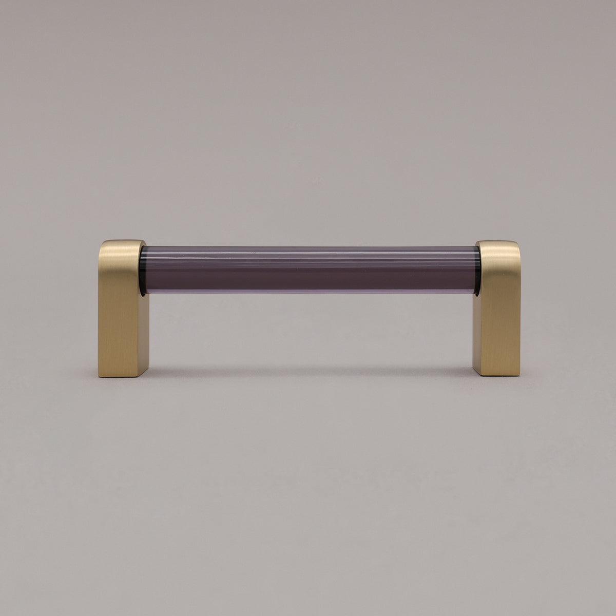 small smoke and satin brass cabinet pull standing on gray background