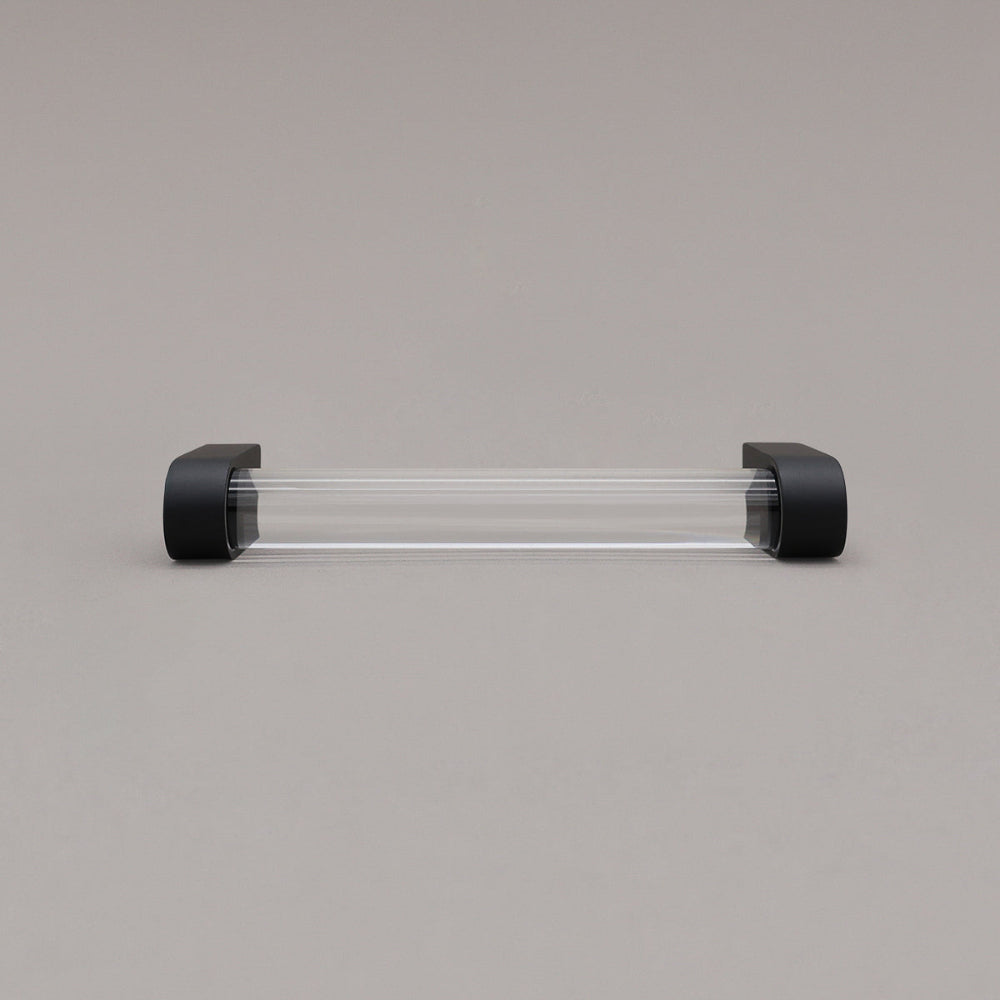 small clear and matte black cabinet pull laying on gray background