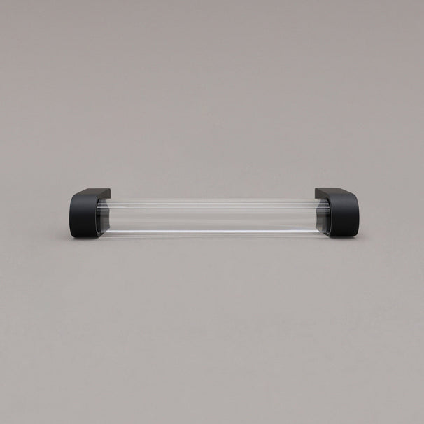 small clear and matte black cabinet pull laying on gray background