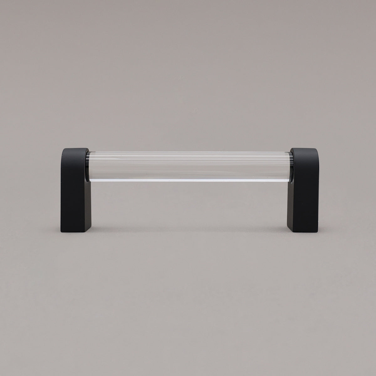 small clear and matte black cabinet pull standing on gray background