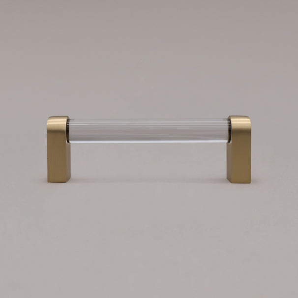 small clear and satin brass cabinet pull standing on gray background