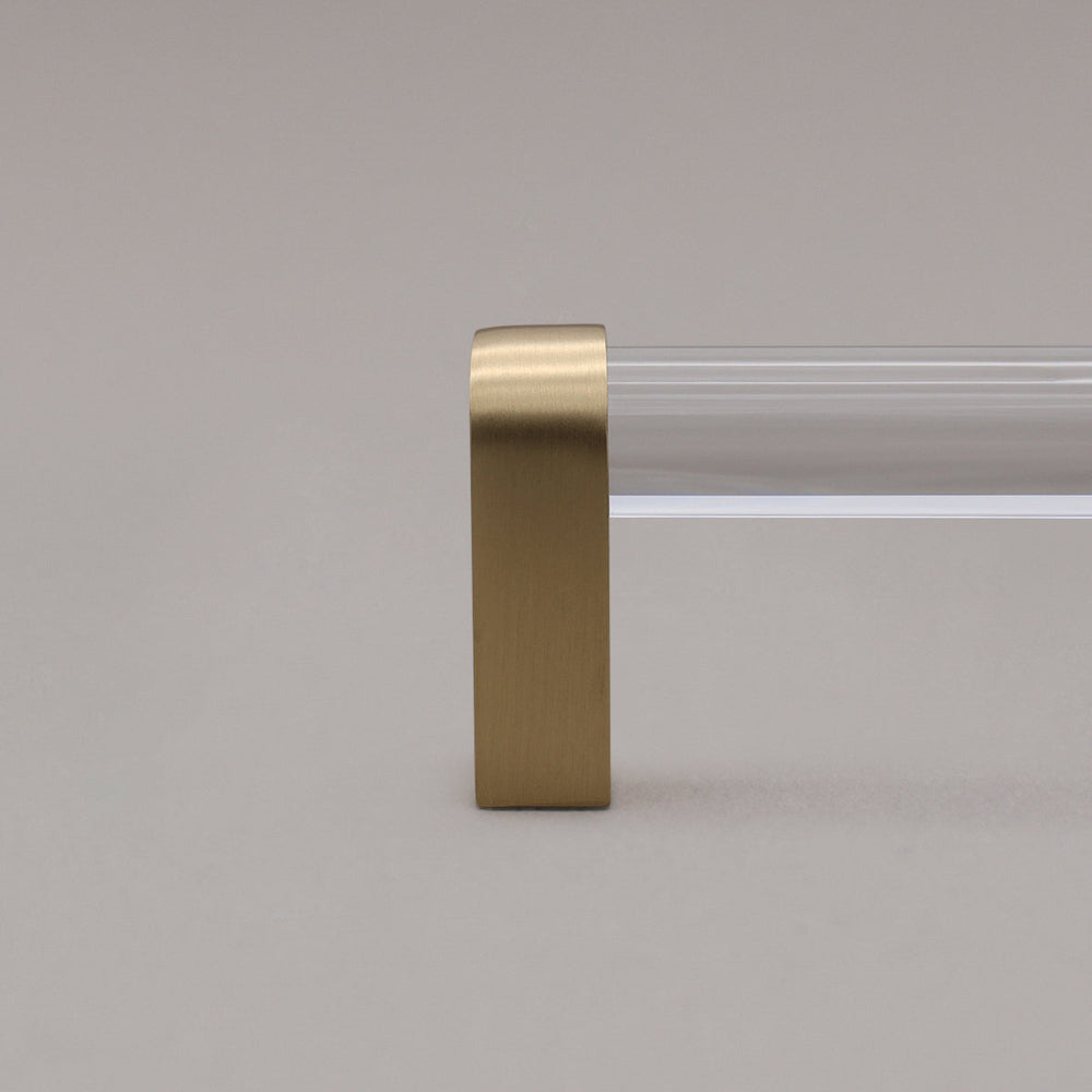 close up of clear and satin brass cabinet pull stem on gray background
