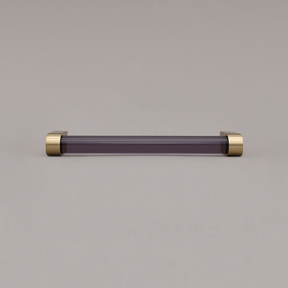 medium smoke and satin brass cabinet pull laying on gray background