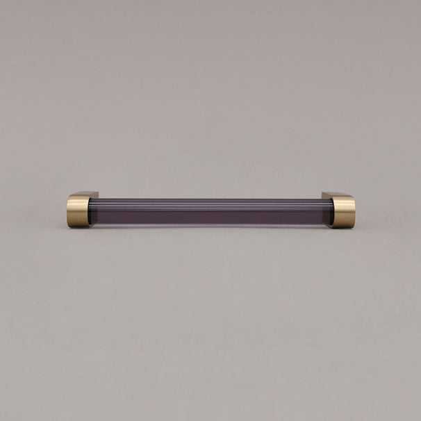 medium smoke and satin brass cabinet pull laying on gray background