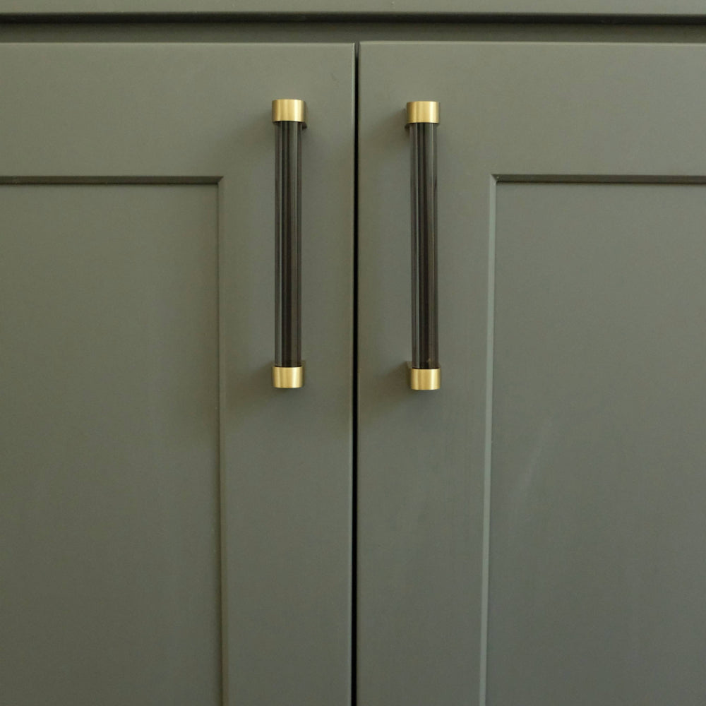 smoke and brass acrylic cabinet pulls installed on blue door