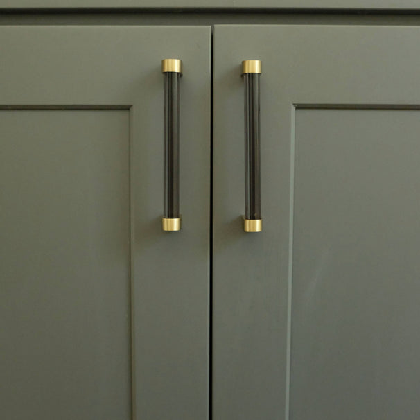 smoke and brass acrylic cabinet pulls installed on blue door