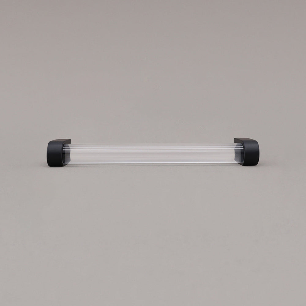 medium clear and matte black cabinet pull laying on gray background