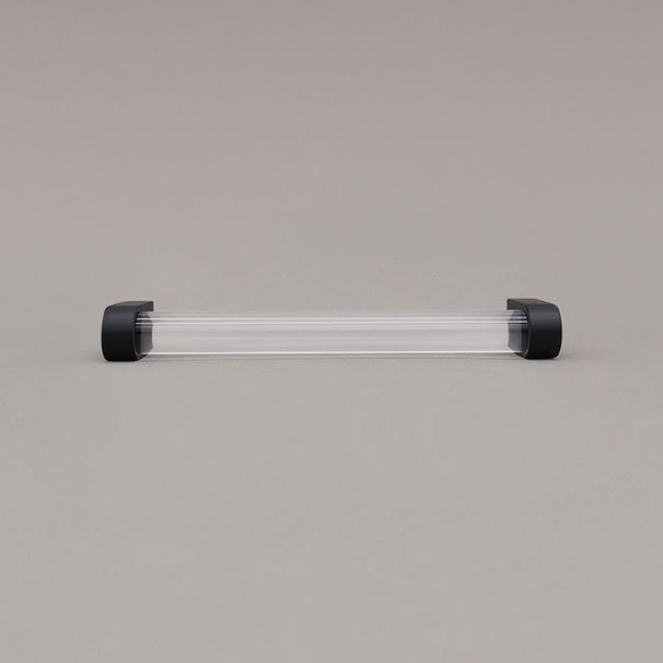 medium clear and matte black cabinet pull laying on gray background