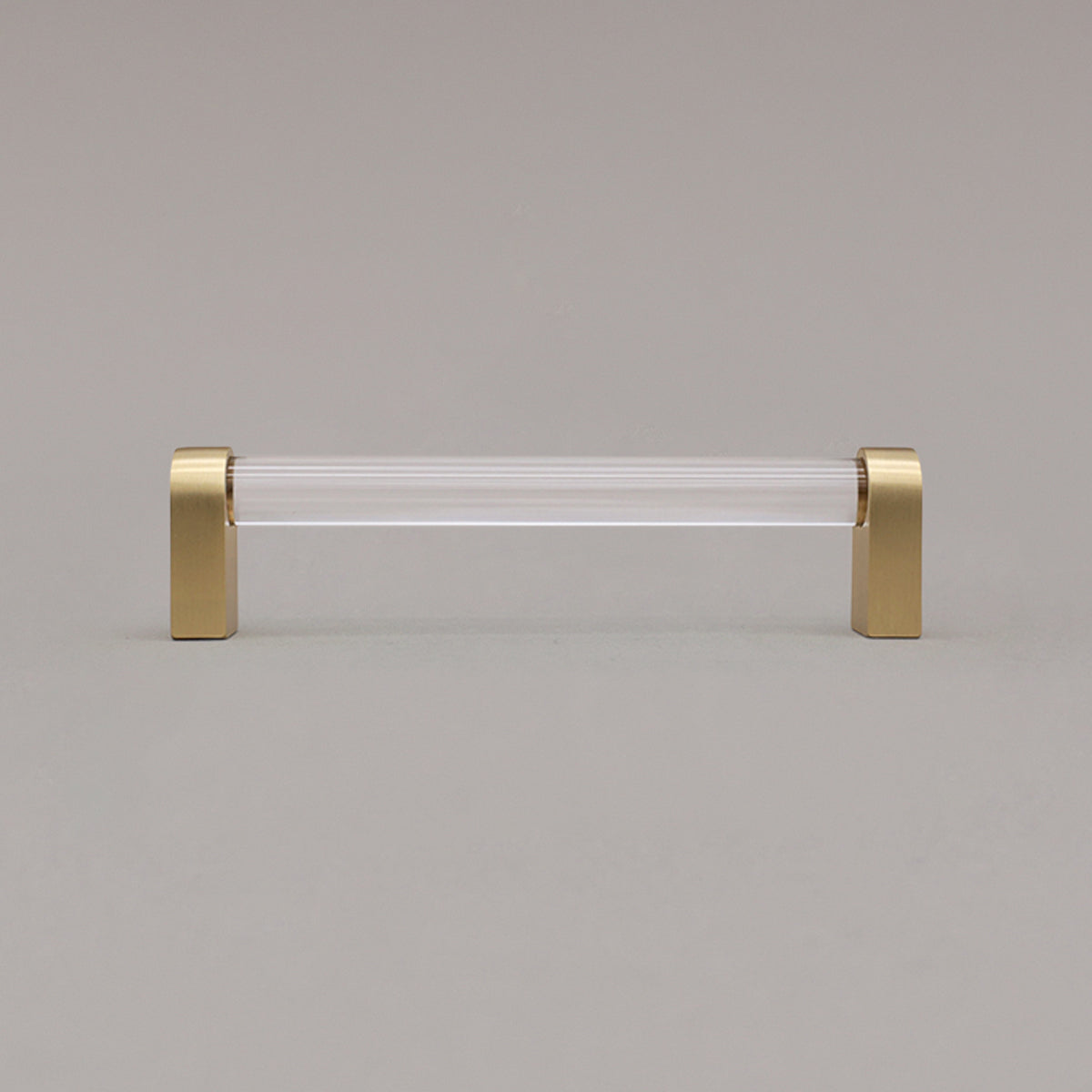 medium clear and satin brass cabinet pull standing on gray background