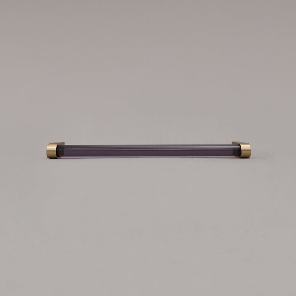 large smoke and satin brass cabinet pull laying on gray background