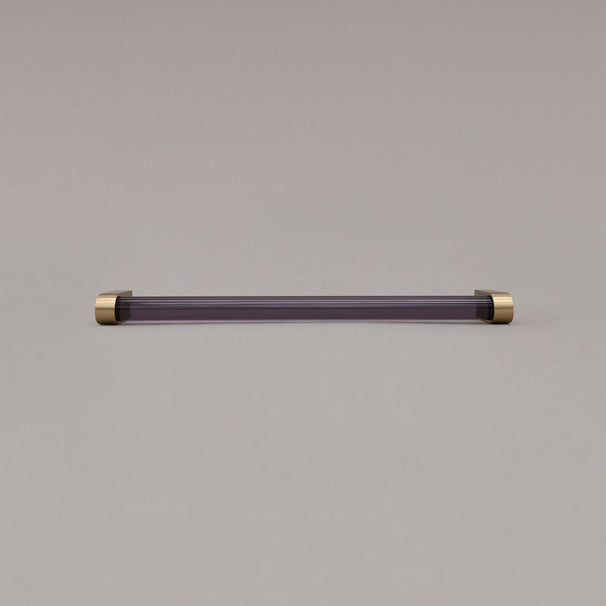 large smoke and satin brass cabinet pull laying on gray background