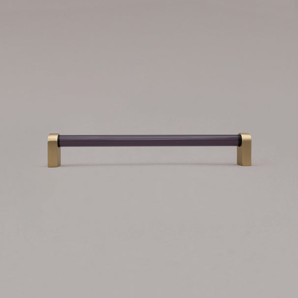 large smoke and satin brass cabinet pull standing on gray background