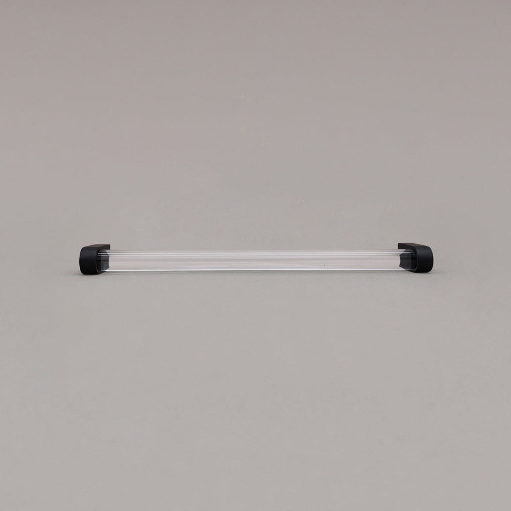 large clear and matte black cabinet pull laying on gray background