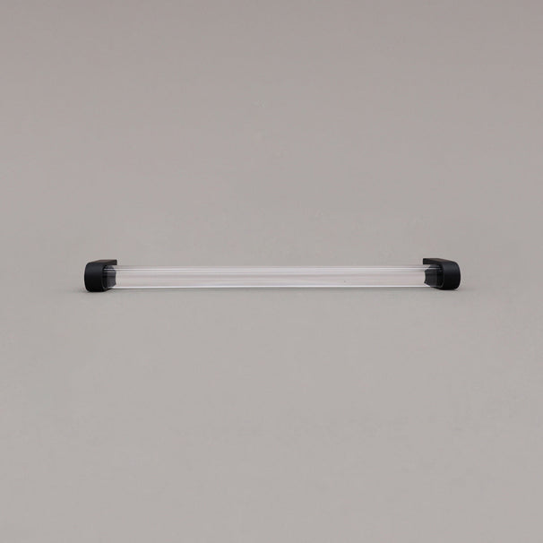 large clear and matte black cabinet pull laying on gray background