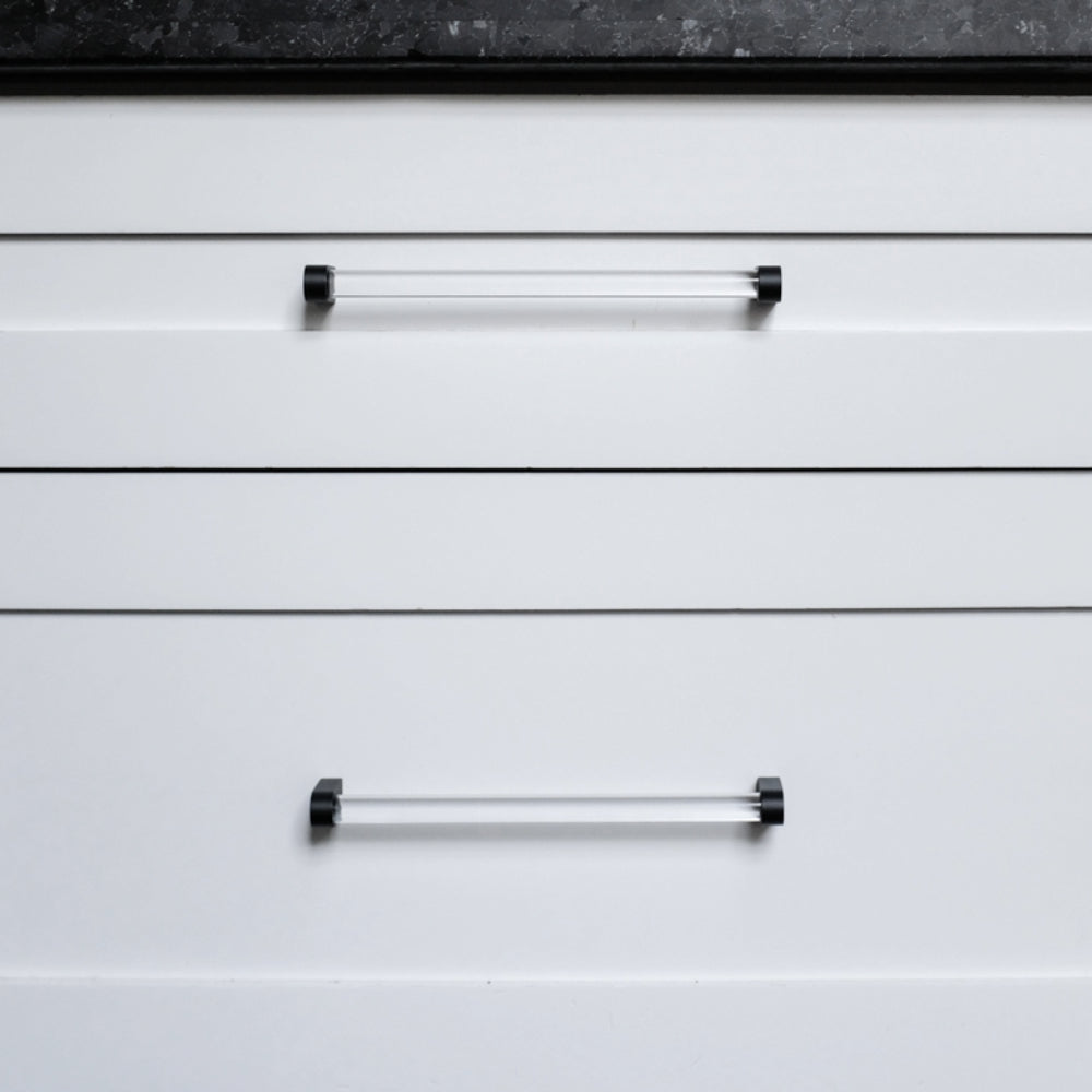 Two clear and matte black pulls on white drawers