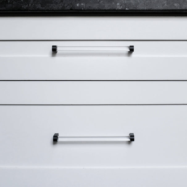 Two clear and matte black pulls on white drawers