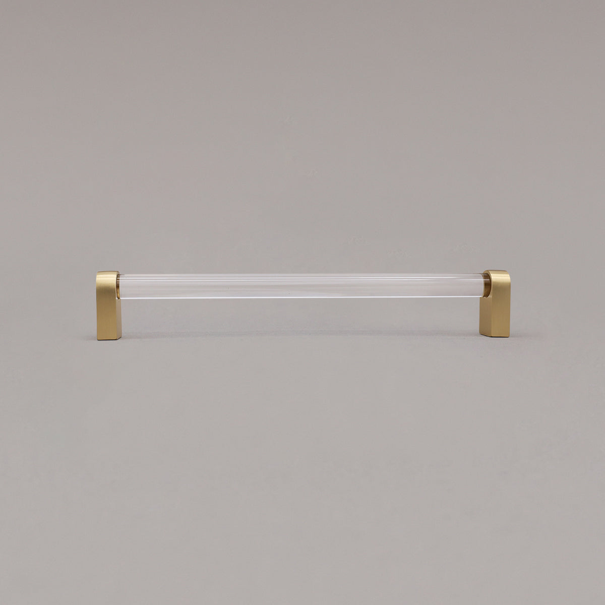 large clear and satin brass cabinet pull standing on gray background