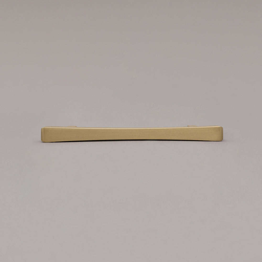 Satin brass gold diamond pull laying down on gray background