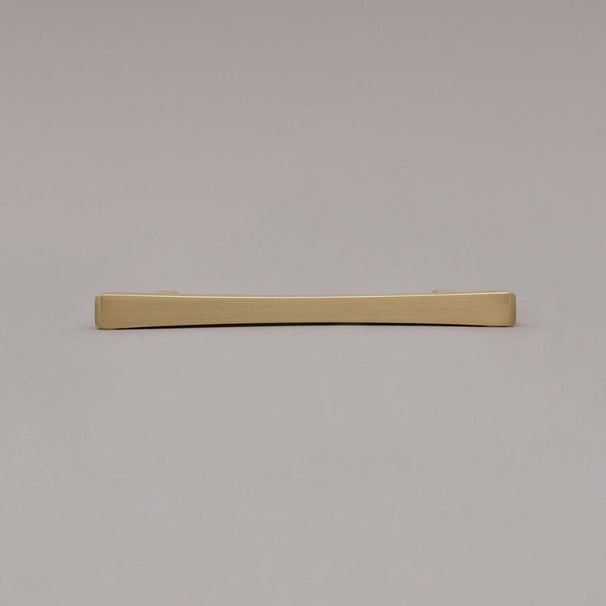 Satin brass gold diamond pull laying down on gray background