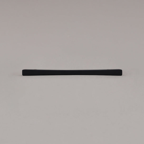Medium matte black diamond cabinet pull laying on gray background