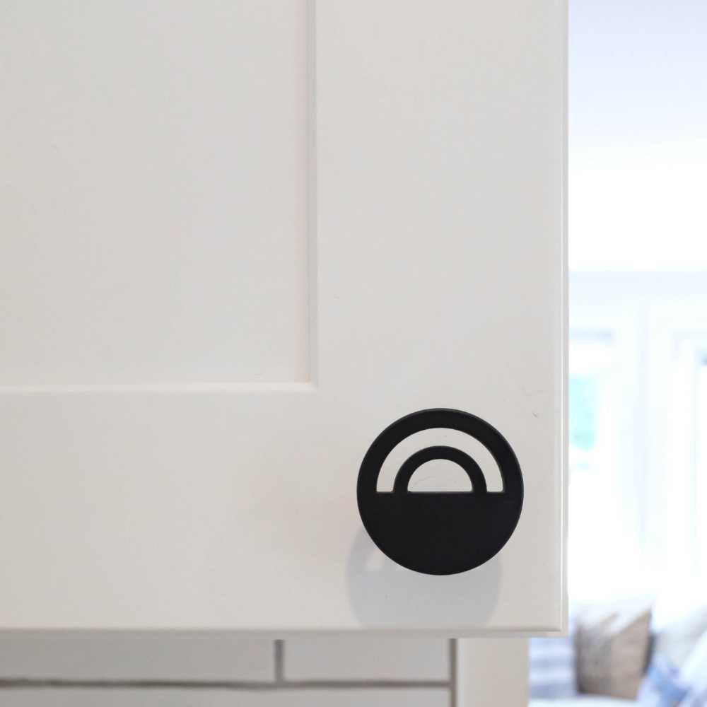 Horizon matte black knob installed on white kitchen cabinet