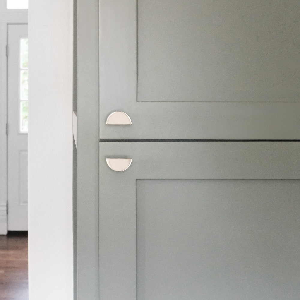 polished nickel half moon knobs installed on blue kitchen cabinet doors