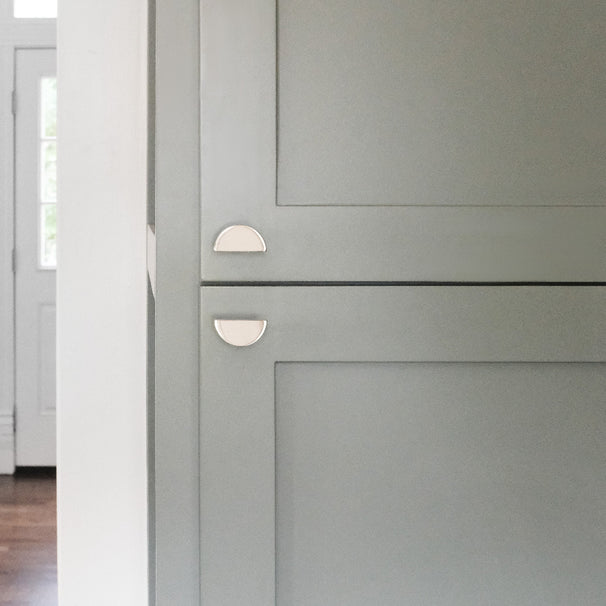 polished nickel half moon knobs installed on blue kitchen cabinet doors