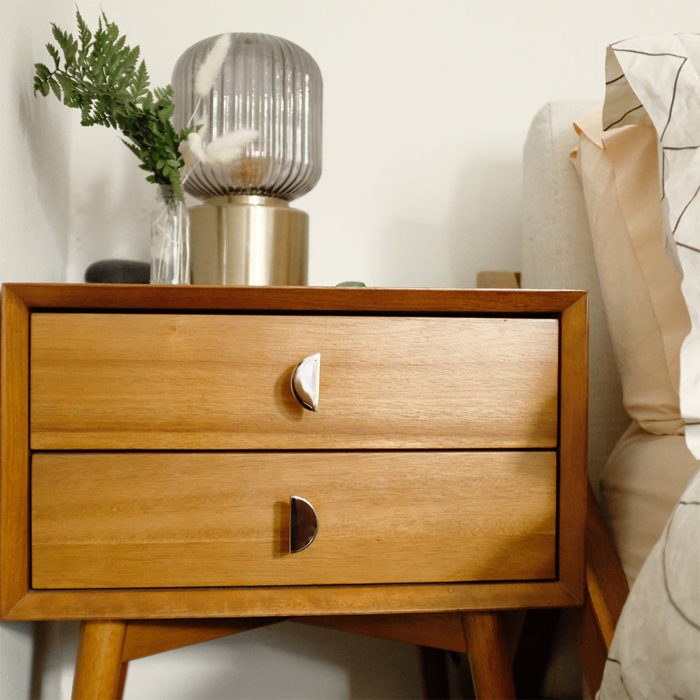 half moon polished nickel knobs installed on wooden bedside table