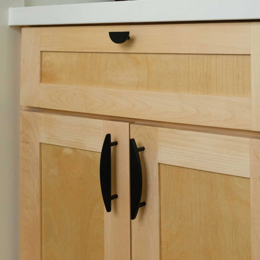 black half moon cabinet pulls and cabinet knob installed on light wooden cabinet