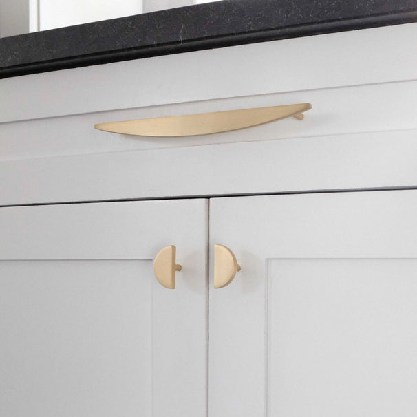 half moon satin brass pull and knobs installed on white cabinets